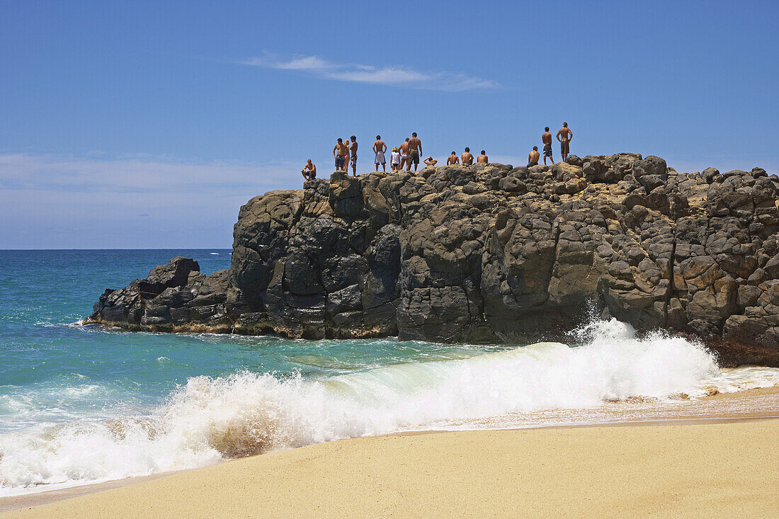 Menschen auf einem Felsen am Strand, Weimea Bay Beach Park, North Shore, Oahu, Hawaii, USA, Amerika