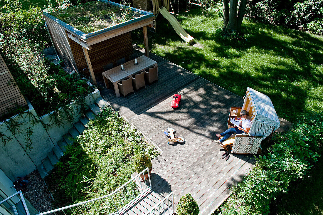 Woman relaxing in a roofed wicker beach chair on a terrace, Hamburg, Germany