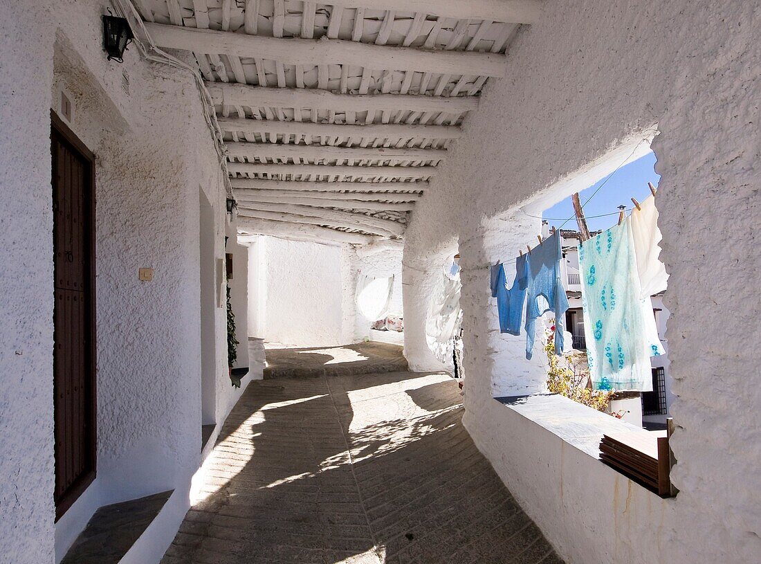 Callejuela típica con las paredes encaladas y ropa tendida en Capileira, localidad situada en el Barranco de Poqueira de las Alpujarras granadinas - Sierra Nevada - Granada - Andalucía - España