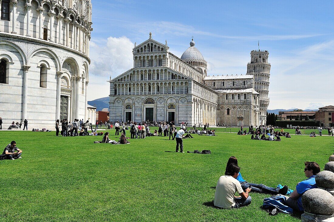 People sitting on the grass in the field of Miracoli in Pisa, Tuscany Region, northern  Itali