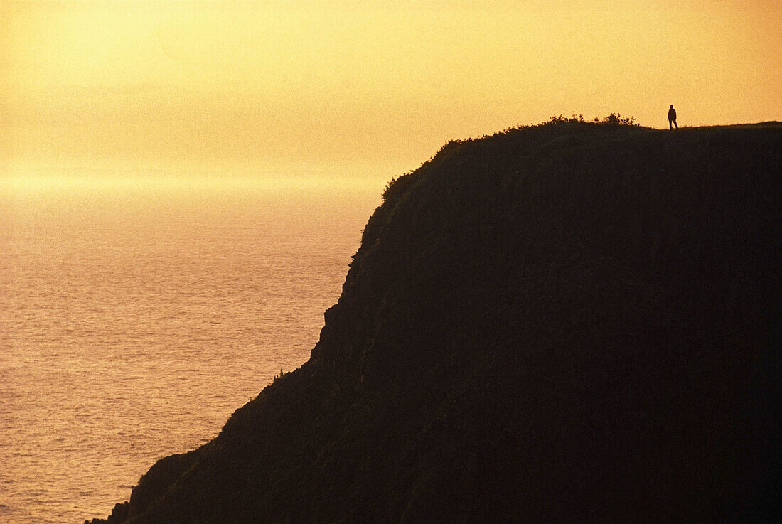 Person standing at top of a cliff, Southern Head at sunset, Grand Manan island, New Brunswick, Canada