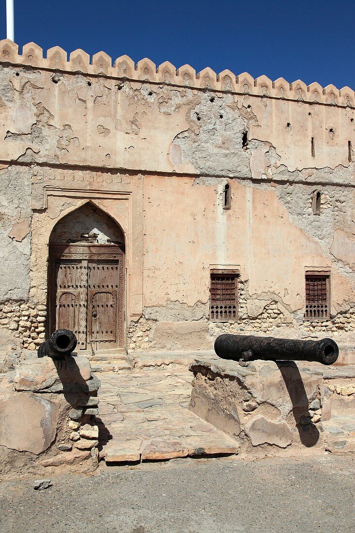 two old traditional cannons in front of the facade of Fort Quriat in the village Quriat, Sultanate of Oman, Asia.