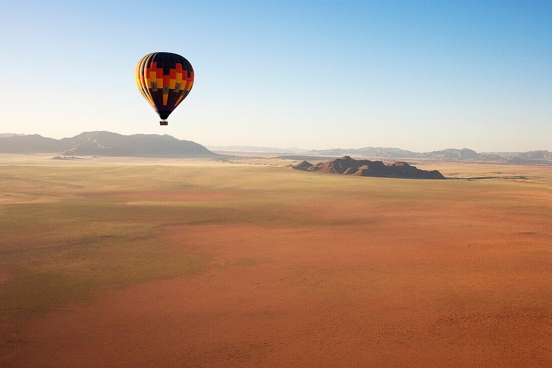 Namibia - The hot-air balloon above a sandy plain at the edge of the Namib Desert In March during the rainy season with a delicate carpet of green desert grass NamibRand Nature Reserve, Namibia