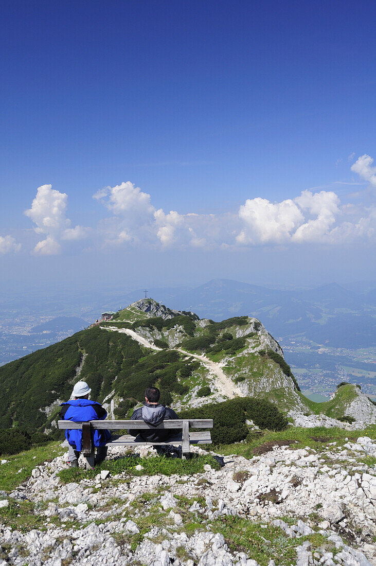 Two hikers sitting on a bench and looking towards Geiereck, Salzburger Hochthron, Untersberg, Berchtesgaden mountain range, Berchtesgaden, Upper Bavaria, Bavaria, Germany