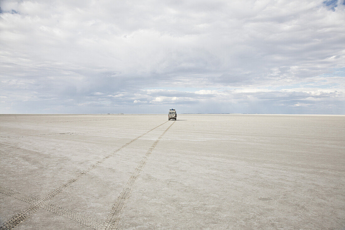 Geländewagen unter Wolkenhimmel, Ntwetwe Salzsee, Botswana, Afrika