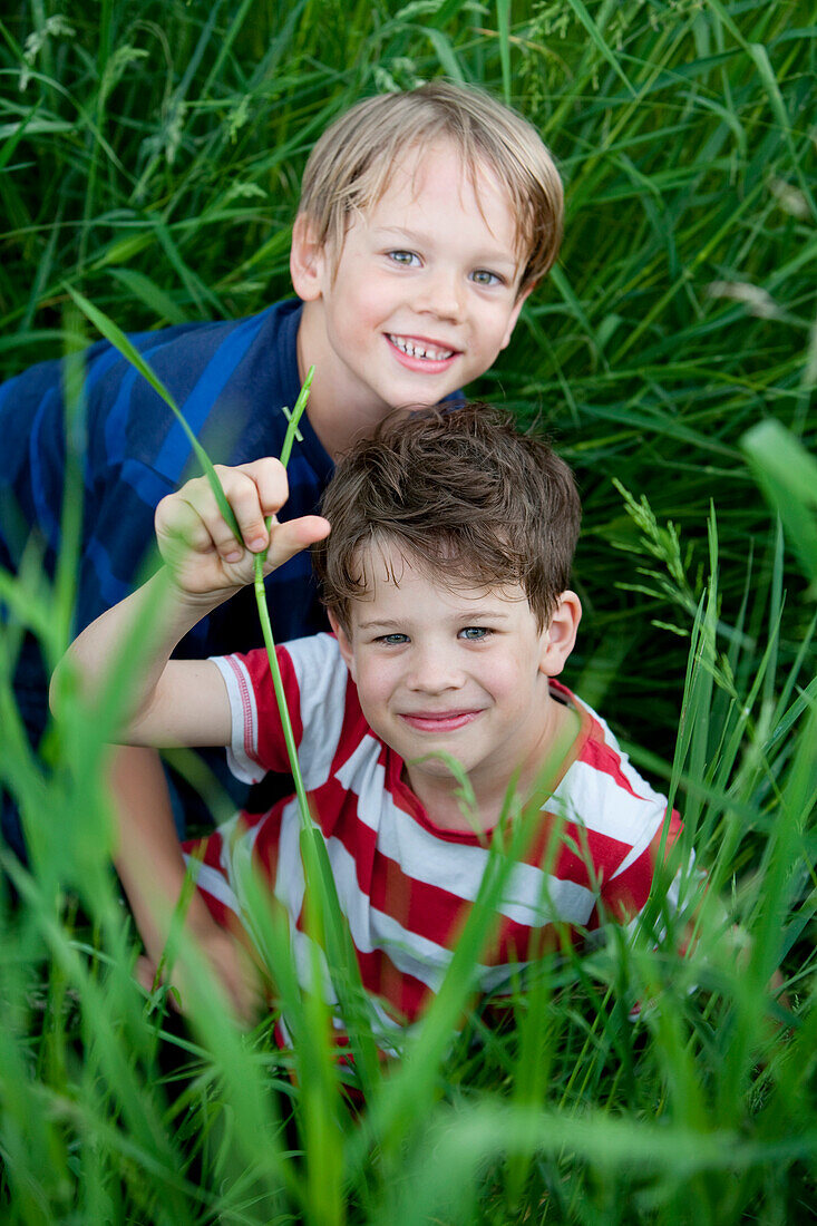 Zwei Jungen (6 - 7 Jahre) sitzen im Gras