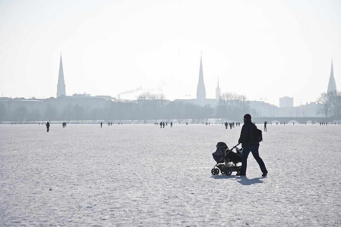 Spaziergänger mit Kinderwagen auf zugefrorener Außenalster im Winter, Hamburg, Deutschland