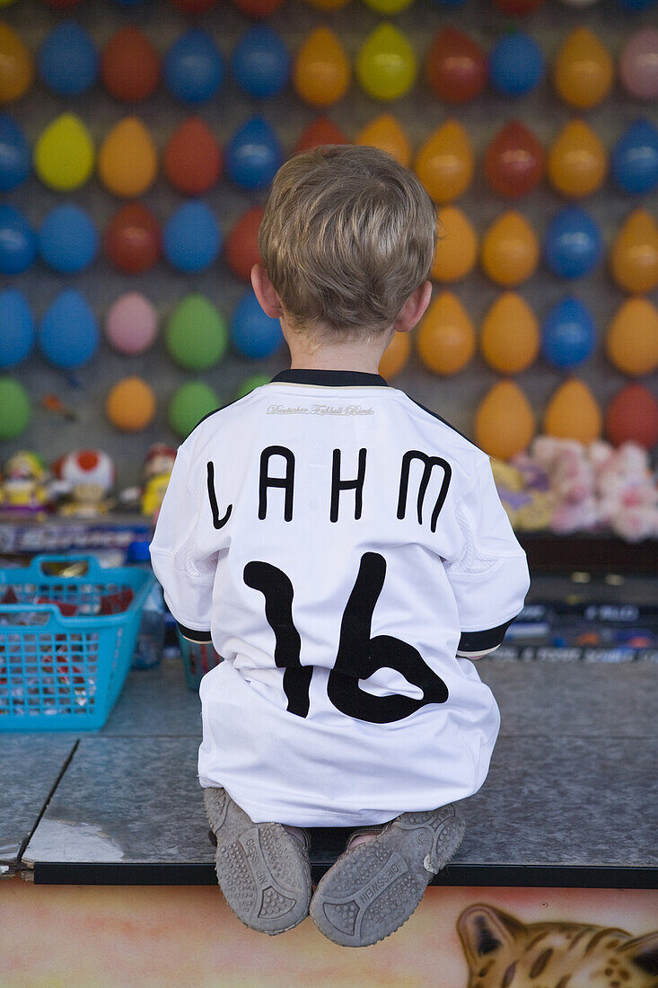 Young boy wearing a Phillip Lahm German National soccer team jersey at a dart booth at a funfair, Rotenburg an der Fulda, Hesse, Germany, Europe