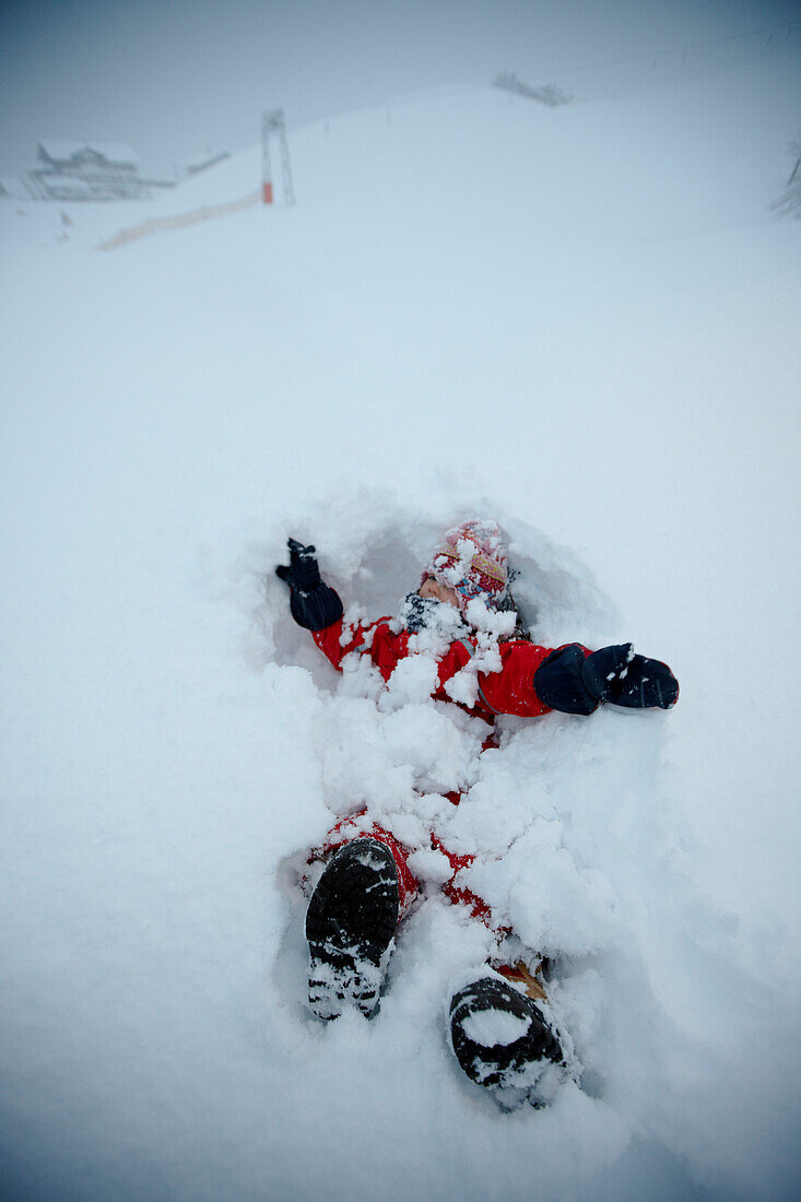 Girl lying in deep snow, Schlosslelift, Hirschegg  Kleinwalsertal, Vorarlberg