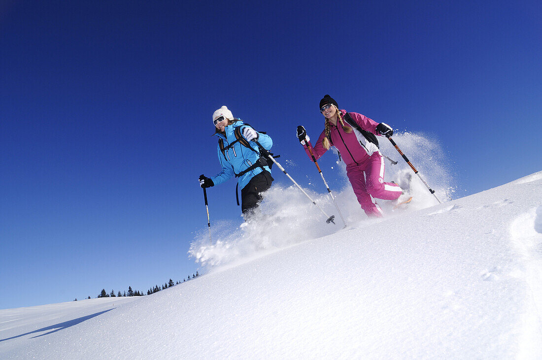 Young women snowshoeing, Hemmersuppenalm, Reit im Winkl, Chiemgau, Upper Bavaria, Bavaria, Germany, Europe