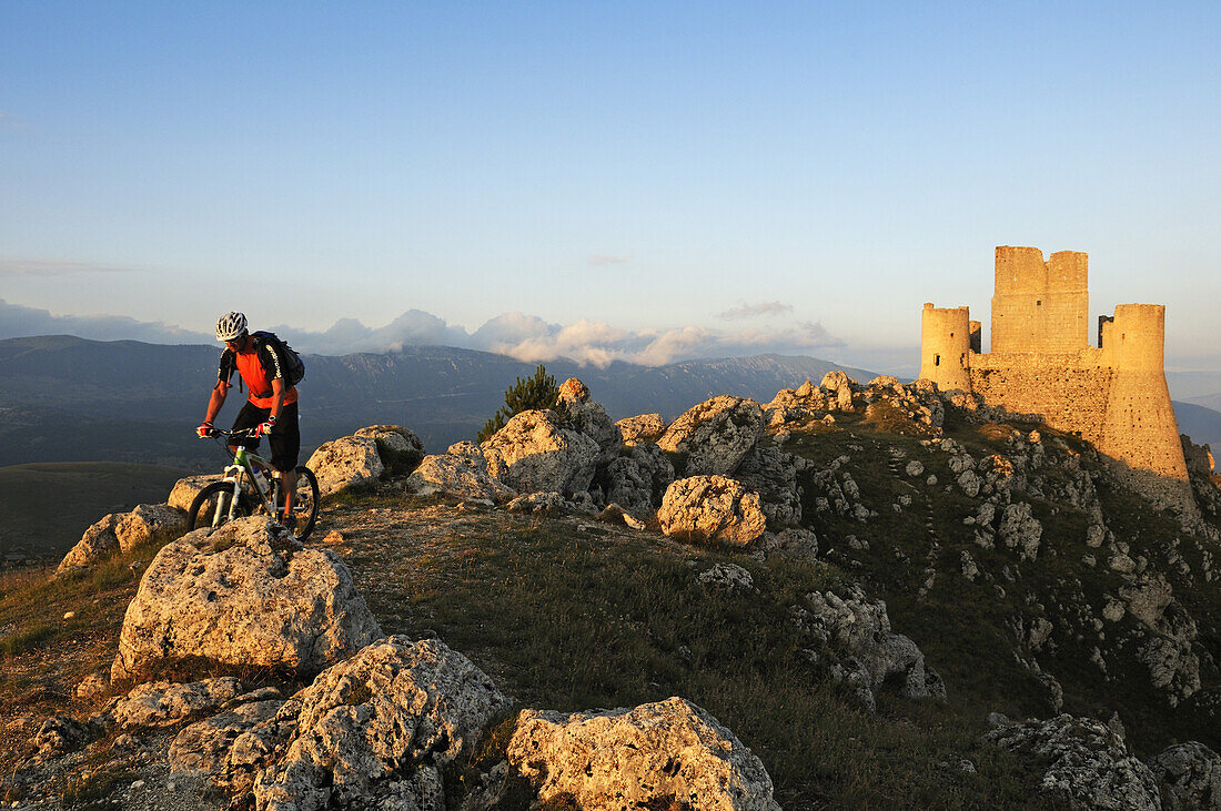 Mountain biker in front of castle Rocca Calascio, Campo Imperatore, Gran Sasso National Park, Abruzzi, Italy, Europe