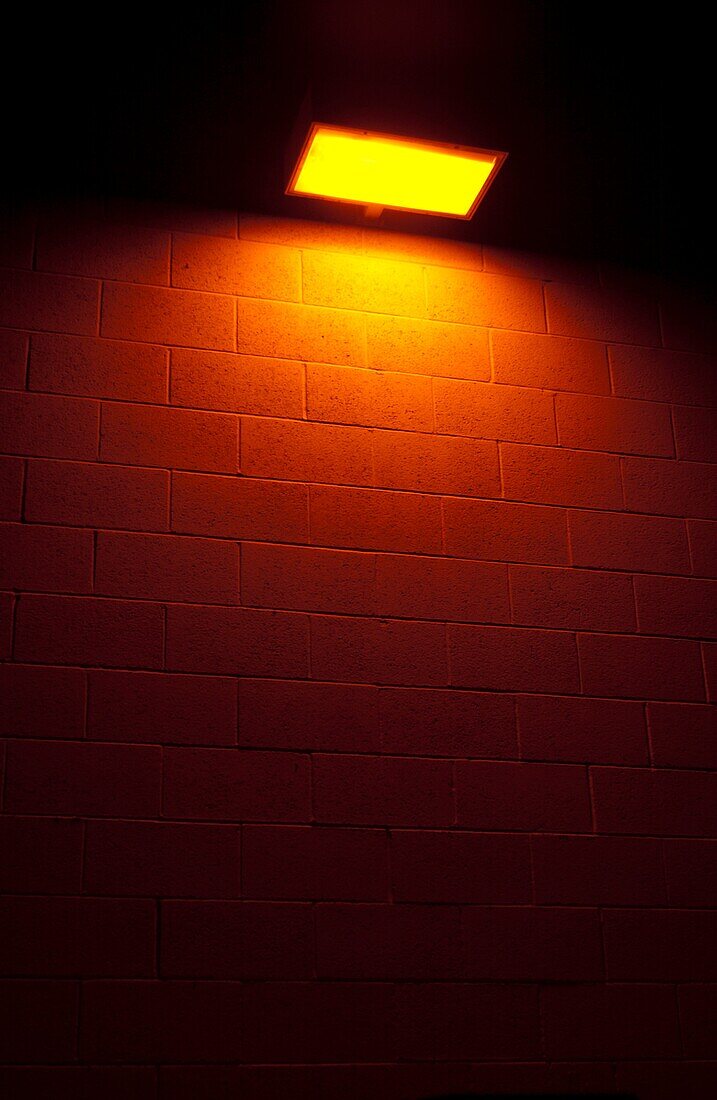 Yellow light casting down over a CMU brick wall