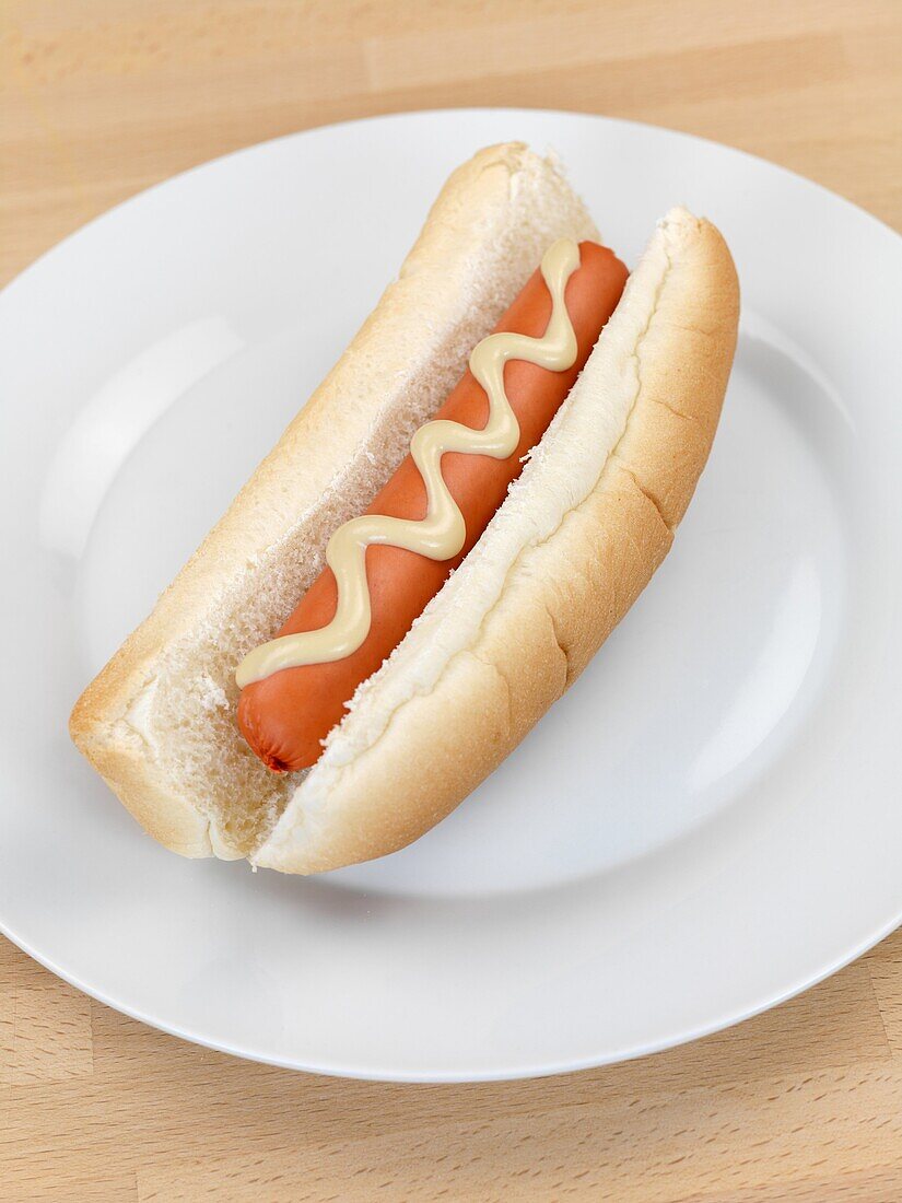 A hotdog with mustard sauce on a kitchen bench