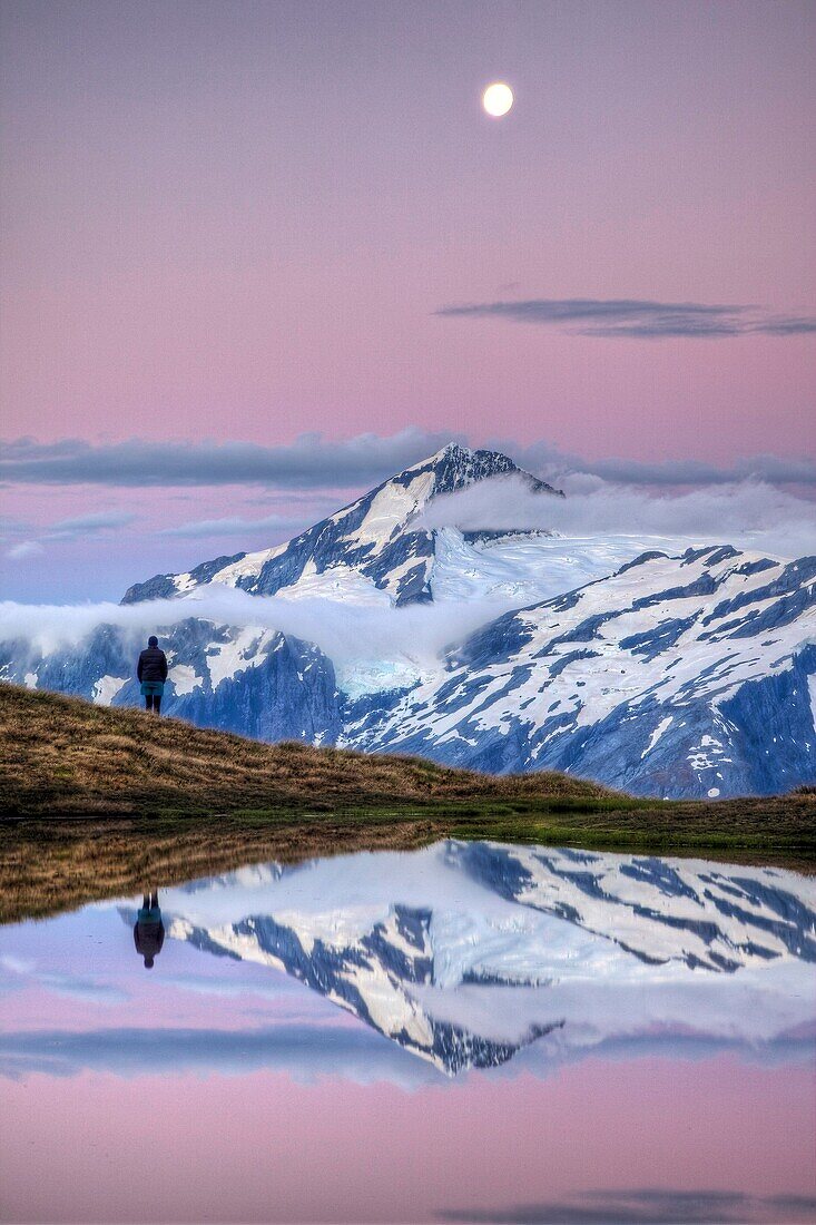 Mt Aspiring, tramper enjoys moonrise at dusk, Cascade saddle tarn, Mount Aspiring National Park, Otago, New Zealand