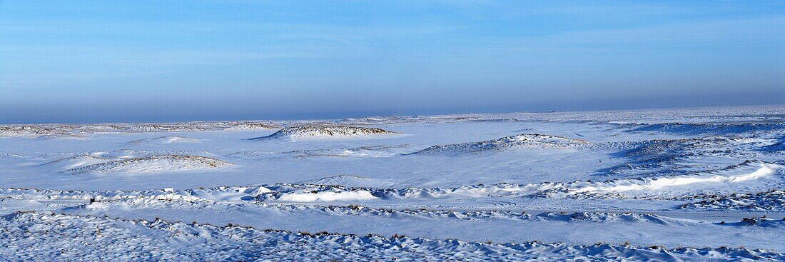 Snow covered landscape with dunes, the North Sea with ice floes and a small lighthouse at the horizon under blue sky, Sylt, North Frisian Islands, Northern Germany, Europe