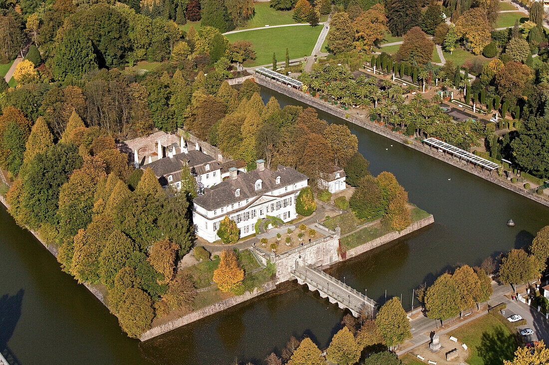 Luftbild von Bad Pyrmonter Schloss, Wasserschloss mit Parkanlage, Bäume mit Herbstlaub und Palmengarten, Niedersachsen, Deutschlnd