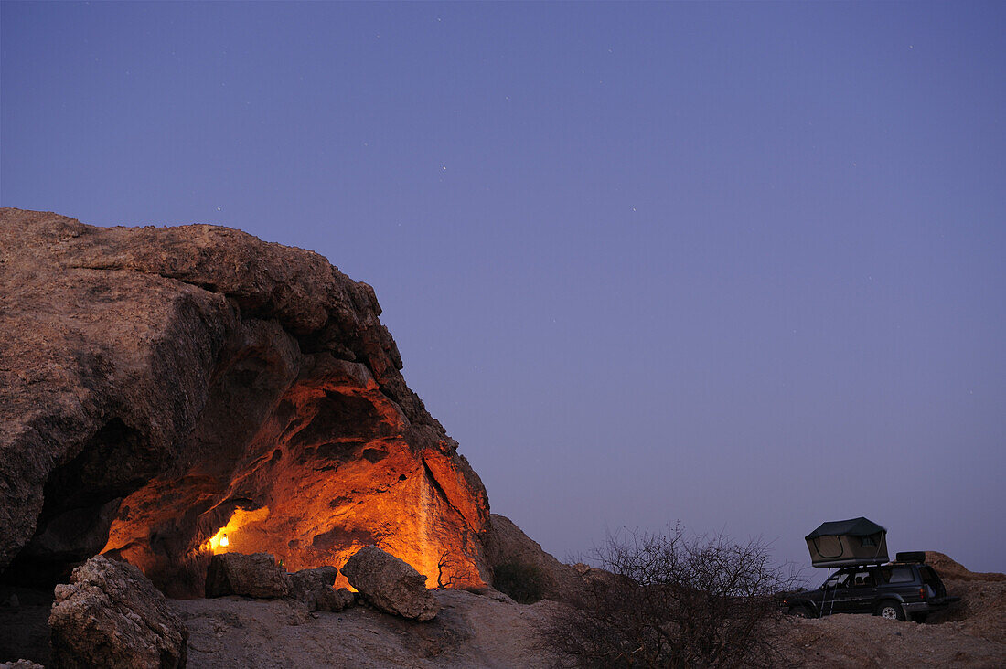 Car with roof tent standing at illuminated overhang, Namib Naukluft National Park, Namib desert, Namib, Namibia