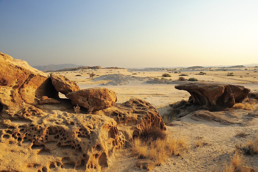 Bizarre Winderosion an Felsen mit Blick auf Savanne, Namibwüste, Namib, Namibia