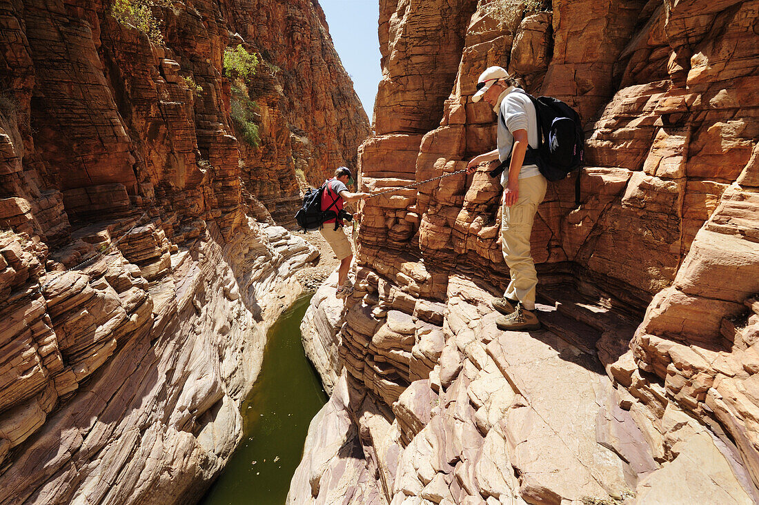 Zwei Personen queren Canyon mit Wasserpool an Versicherung, Olive Trail, Naukluftberge, Namib Naukluft National Park, Namibia
