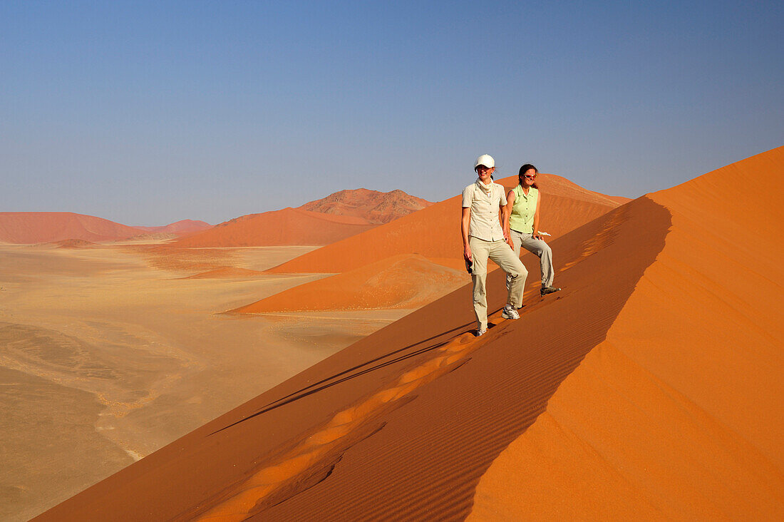 Two women standing on red sand dune in Sossusvlei, dune 45, Sossusvlei, Namib Naukluft National Park, Namib desert, Namib, Namibia