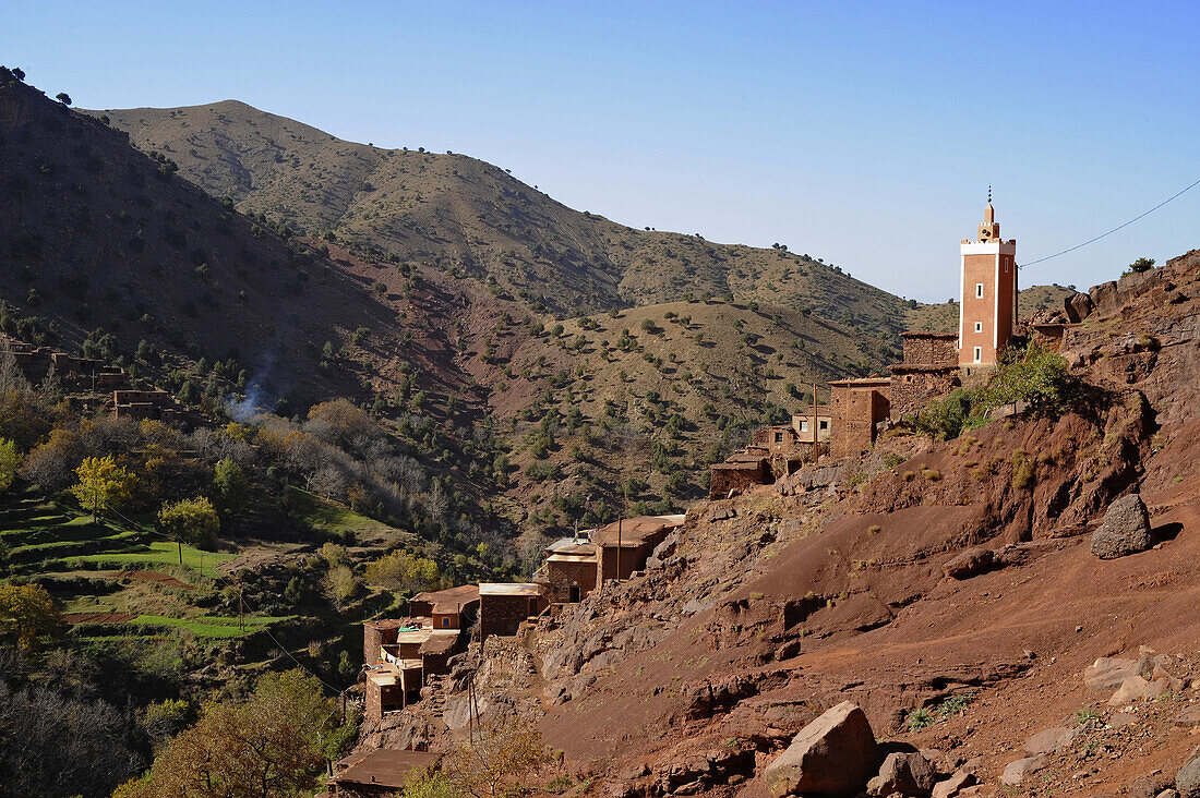 Village on red mountain slopes and gren fields, trekking in the High Atlas from Imlil, Toubkal Area, Morocco