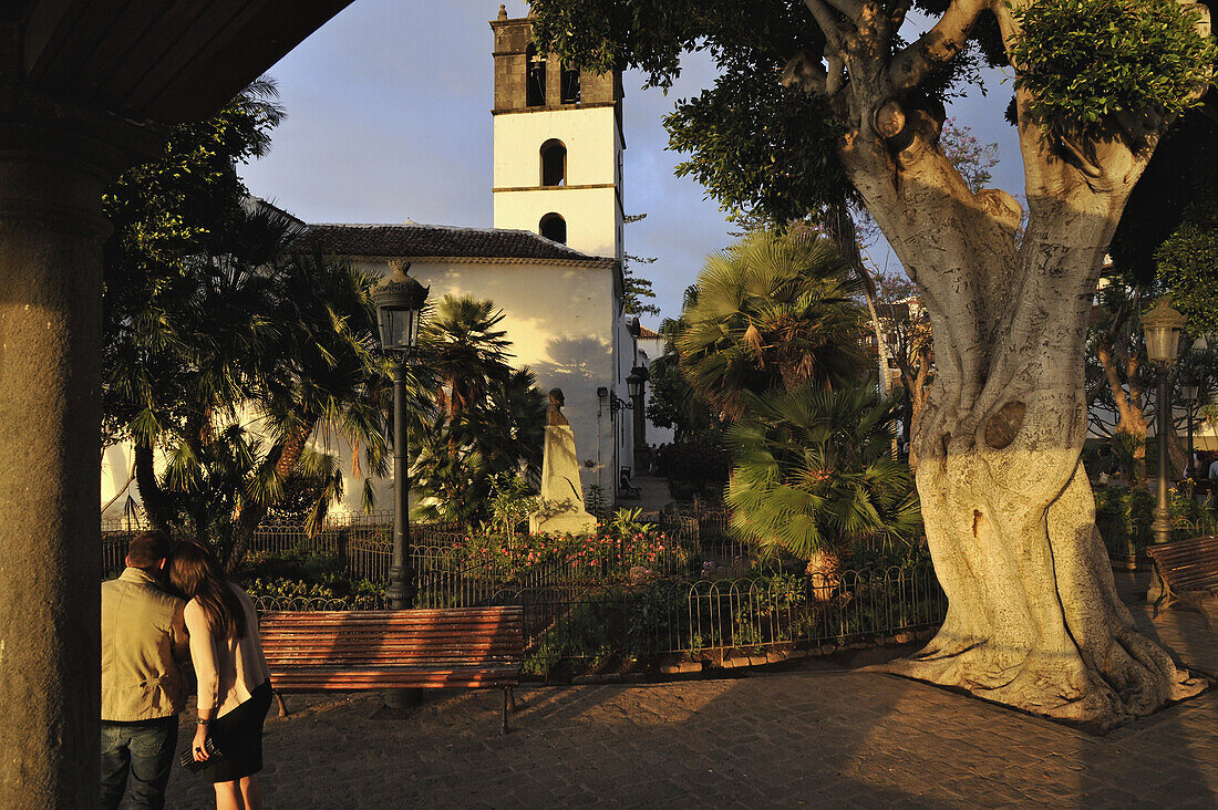 Couple and church at the Plaza Lorenzo Caceres, Icod de los Vinos, Northwest Tenerife, Spain