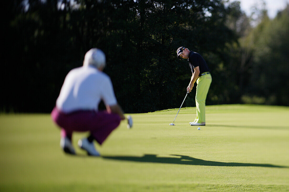 Two men playing golf, Prien am Chiemsee, Bavaria, Germany