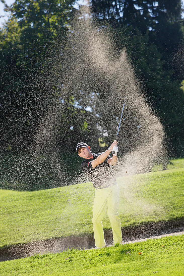 Golfer hitting out of bunker, Prien am Chiemsee, Bavaria, Germany