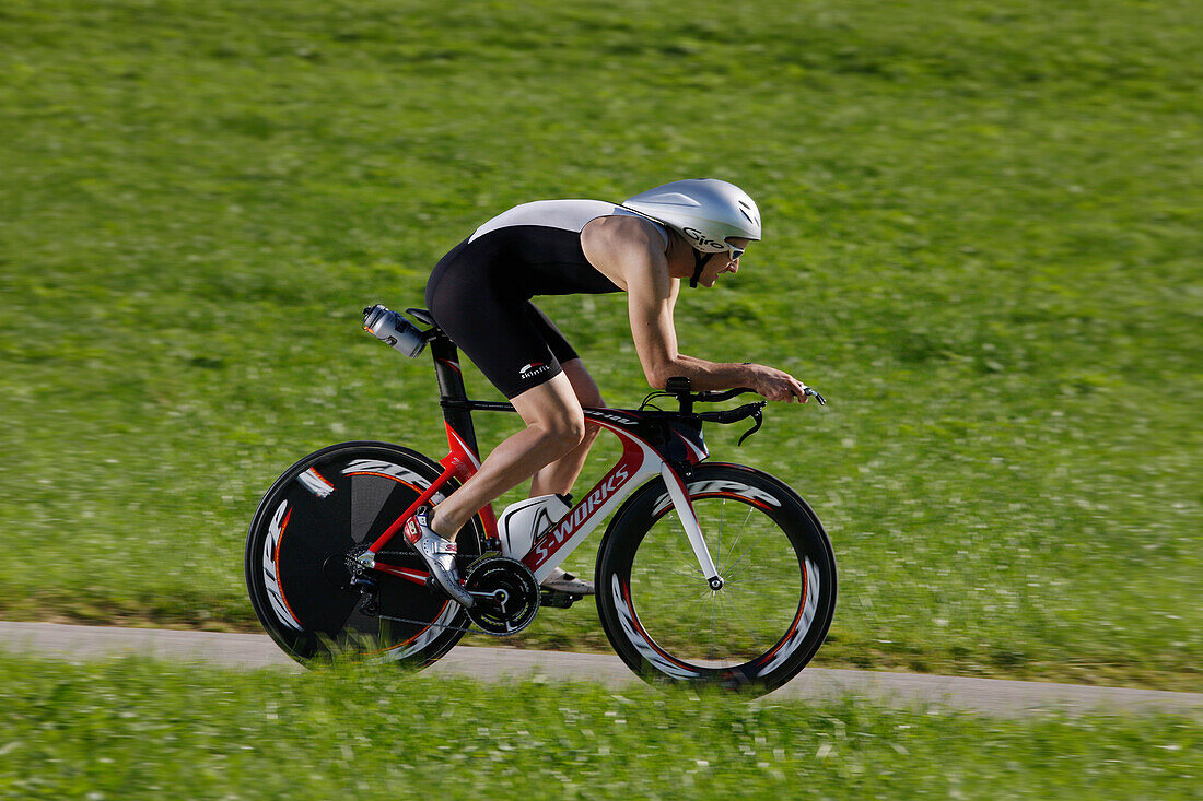 Male racing cyclist with disc wheel on road near Munsing, Upper Bavaria, Germany