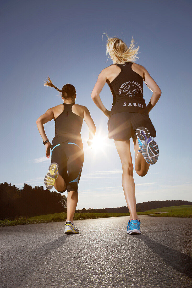 Two female runners on road near Munsing, Upper Bavaria, Germany