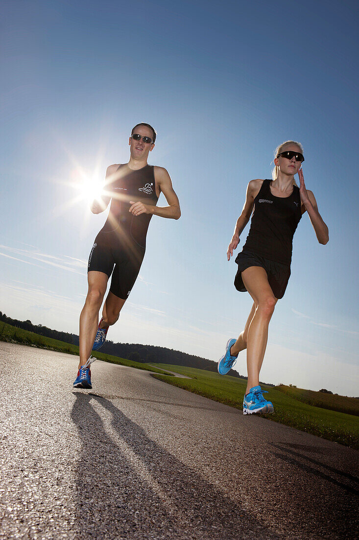 Two runners on road near Munsing, Upper Bavaria, Germany