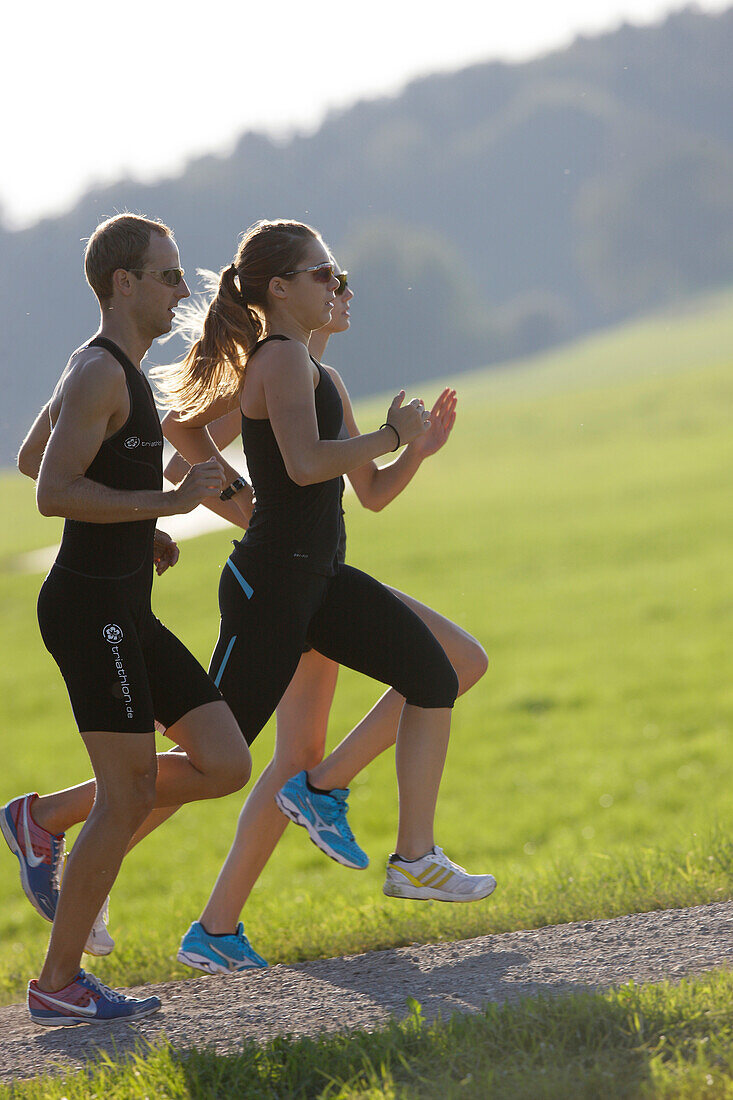 Three runners on dirt track near Munsing, Upper Bavaria, Germany