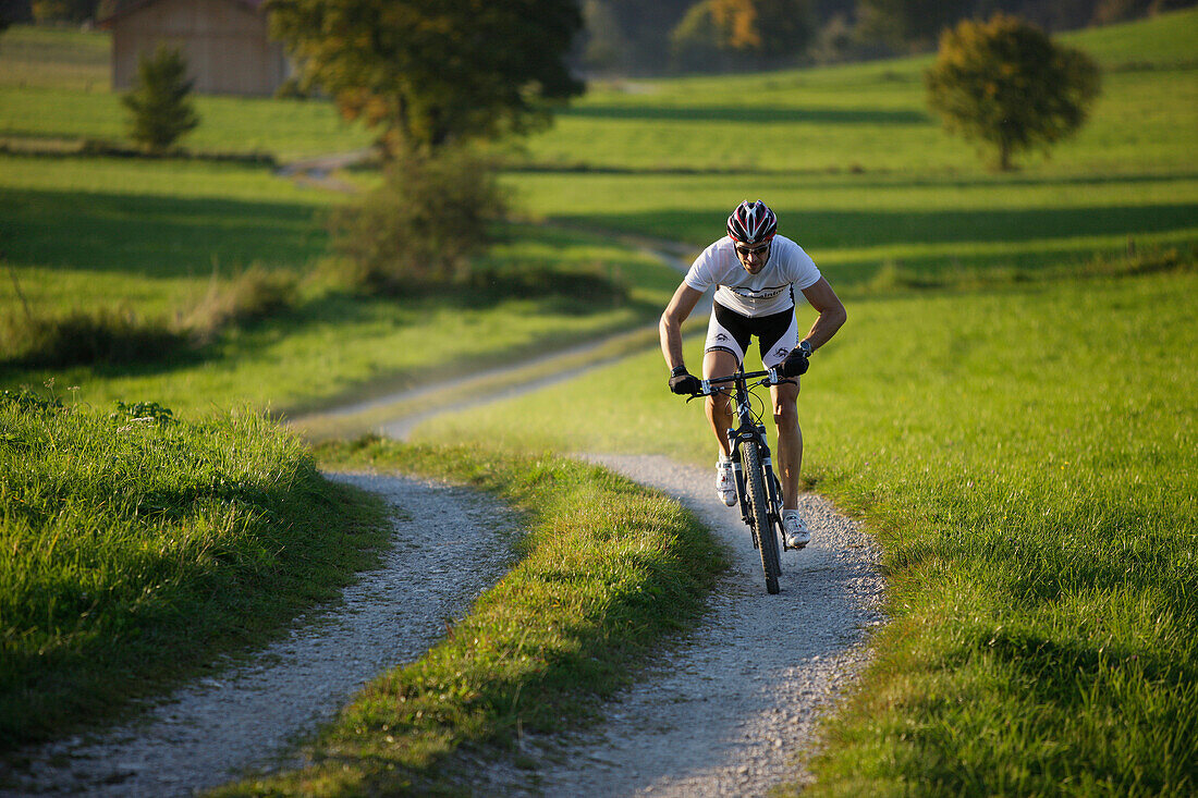 Man mountain biking on dirt track near Munsing, Upper bavaria, Germany