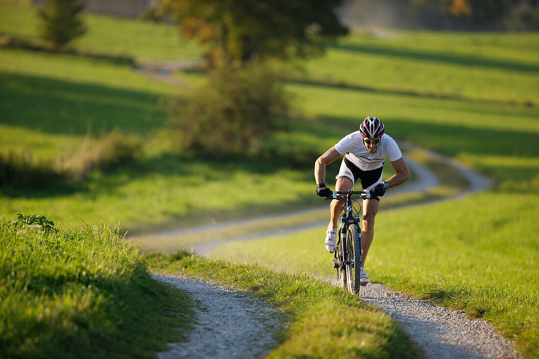 Man mountain biking on dirt track near Munsing, Upper bavaria, Germany