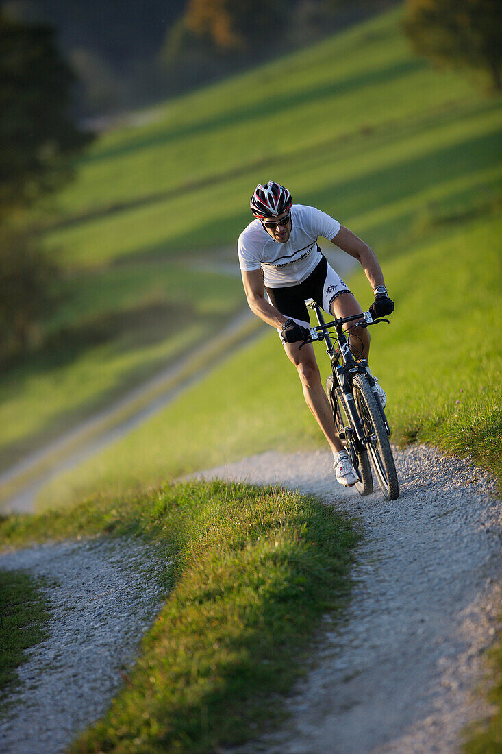 Man mountain biking on dirt track near Munsing, Upper bavaria, Germany