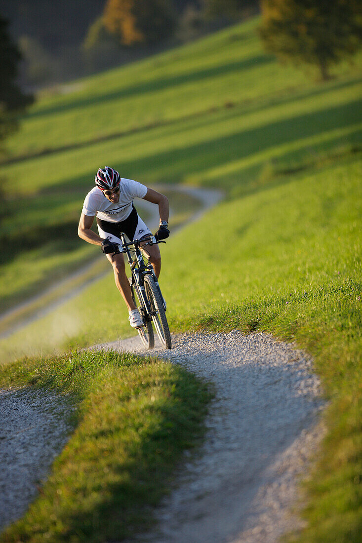 Man mountain biking on dirt track near Munsing, Upper bavaria, Germany