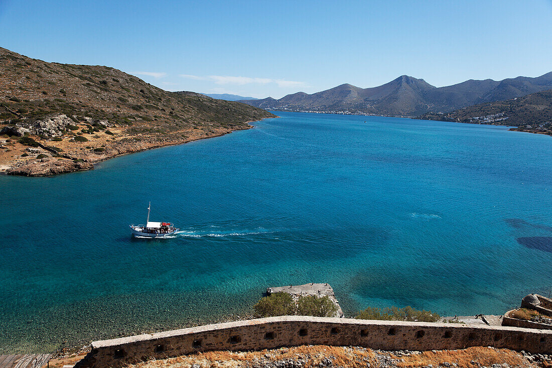 Excursion boat seen from the Venetian fortress, Island of Spinalonga, Lasithi prefecture, Gulf of Mirabella, Crete, Greece