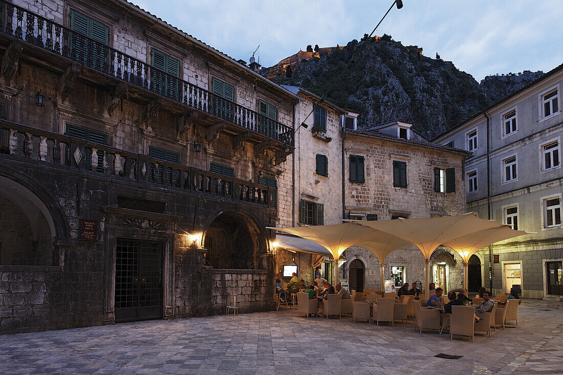 Restaurant auf einem Platz am Abend, im Hintergrund Festung auf dem Hügel, Kotor, Montenegro, Europa