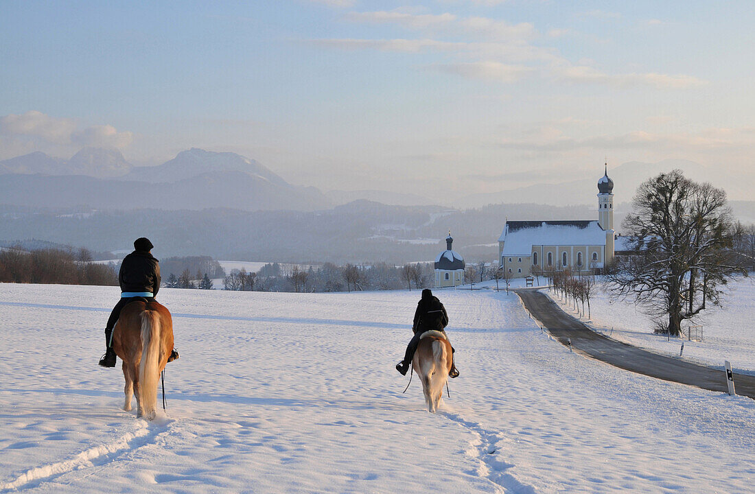 Riders at the church of the holy Marinus and Anian in Wilparting near Irschenberg, Winter in Bavaria, Germany, Europe