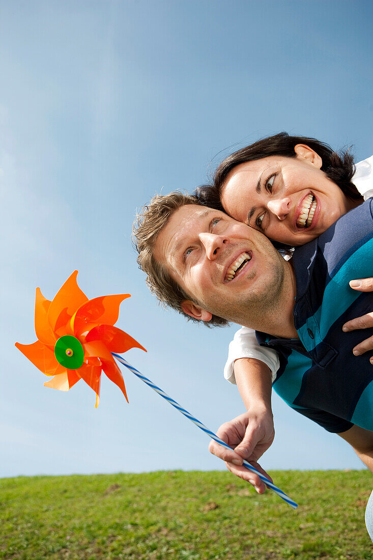 Mid adult man giving woman with pinwheel a piggyback ride