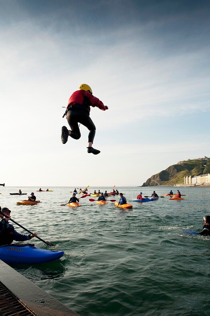 Members of Aberystwyth Kayak Club kayaking and jumping into the sea at Aberystwyth Wales UK