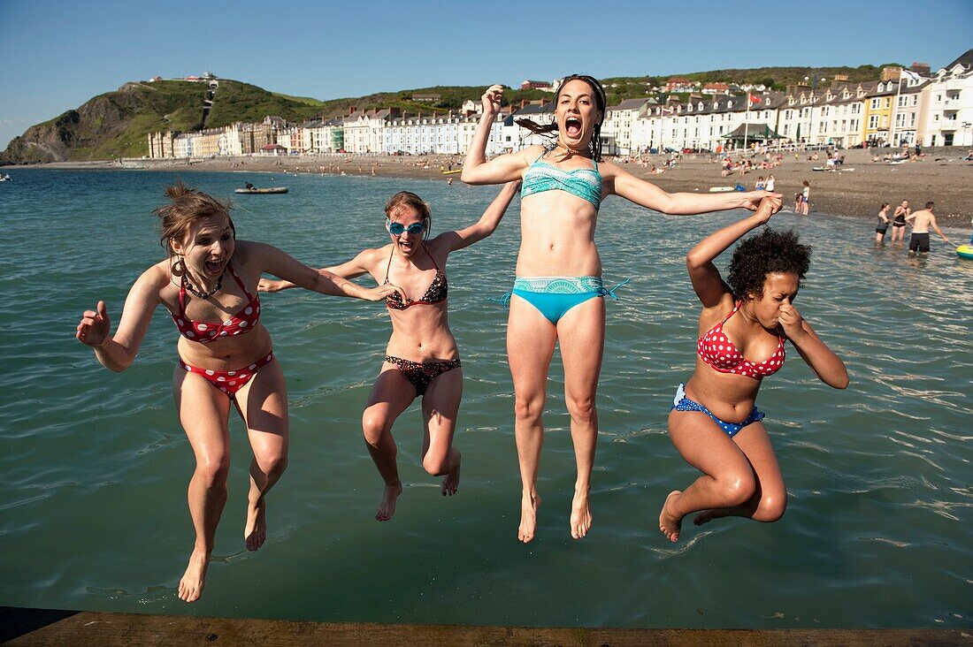 Four young women Aberystwyth university students jumping into the sea at the end of the academic year, June 2009, Wales UK