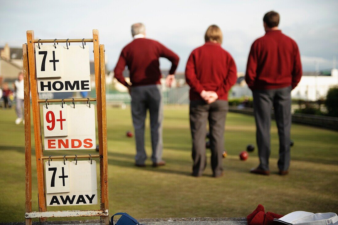 Men playing a game of lawn green bowls on a summer evening, Aberystwyth Wales UK