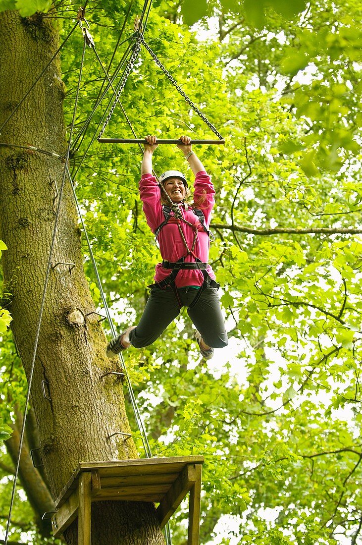 Teenagers on high ropes in the trees as part of a course organised by the Canolfan Yr Urdd outward bound adventure centre, Glanllyn, Bala, North Wales UK