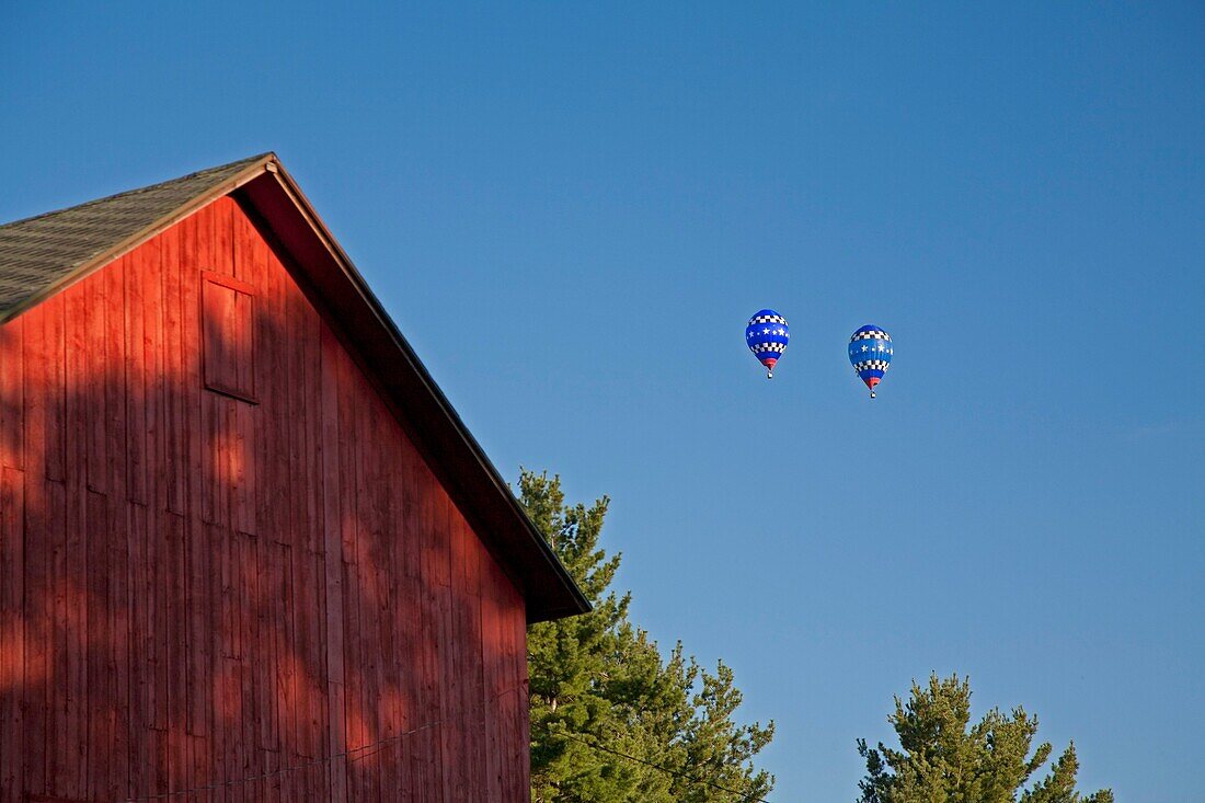 Battle Creek, Michigan - The National Hot Air Balloon Championships Two balloons float over a barn