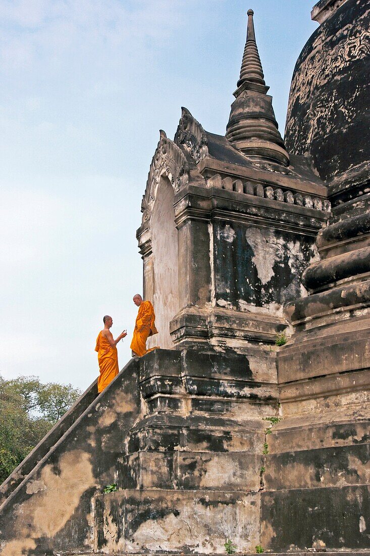 Buddhist monks on the stairs of chedi in Wat Phra Si Sanphet, a Buddhist temple in Ayutthaya, Thailand