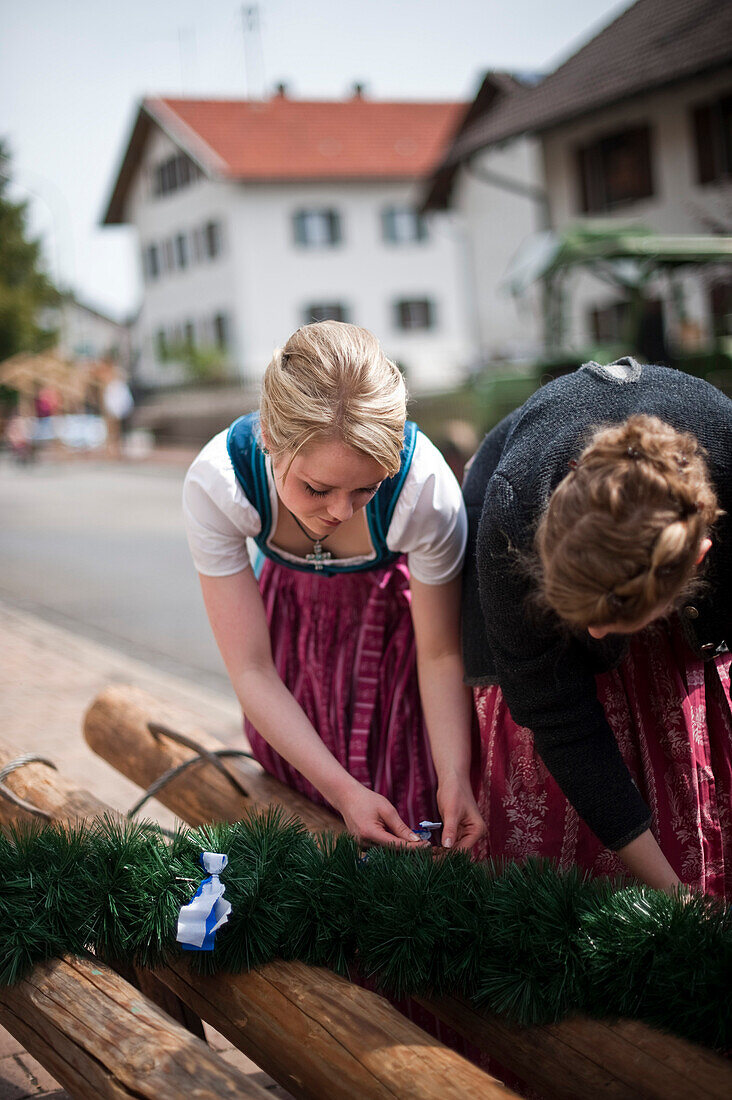 Two women preparing decoration for the Maypole celebration, Sindelsdorf, Weilheim-Schongau, Bavarian Oberland, Upper Bavaria, Bavaria, Germany