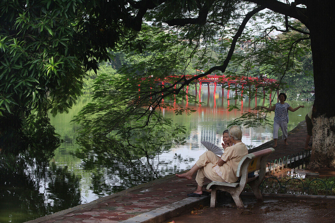 Zwei alte Frauen auf einer Bank beim Reden und Tai-chi, The-Huc-Brücke, See Hoan Kiem, Vietnam, Asien