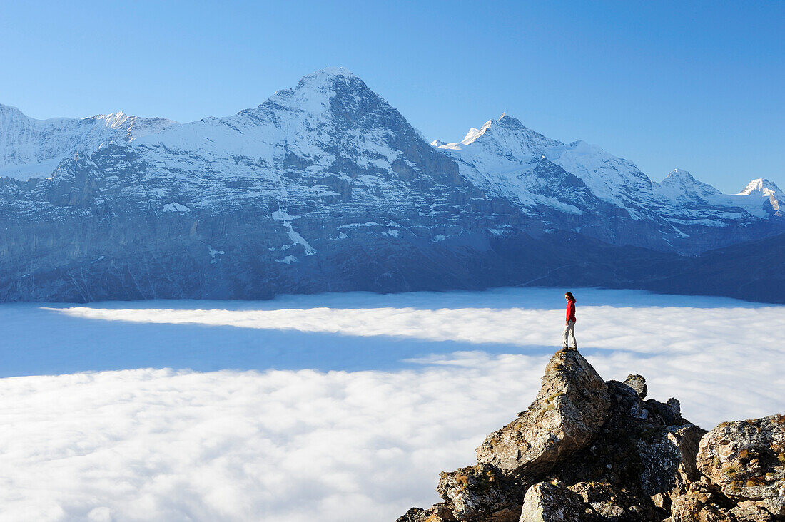 Frau steht auf Felsen und blickt auf Eiger und Jungfrau über Nebelmeer, Bussalp, Grindelwald, UNESCO Welterbe Schweizer Alpen Jungfrau - Aletsch, Berner Oberland, Bern, Schweiz, Europa