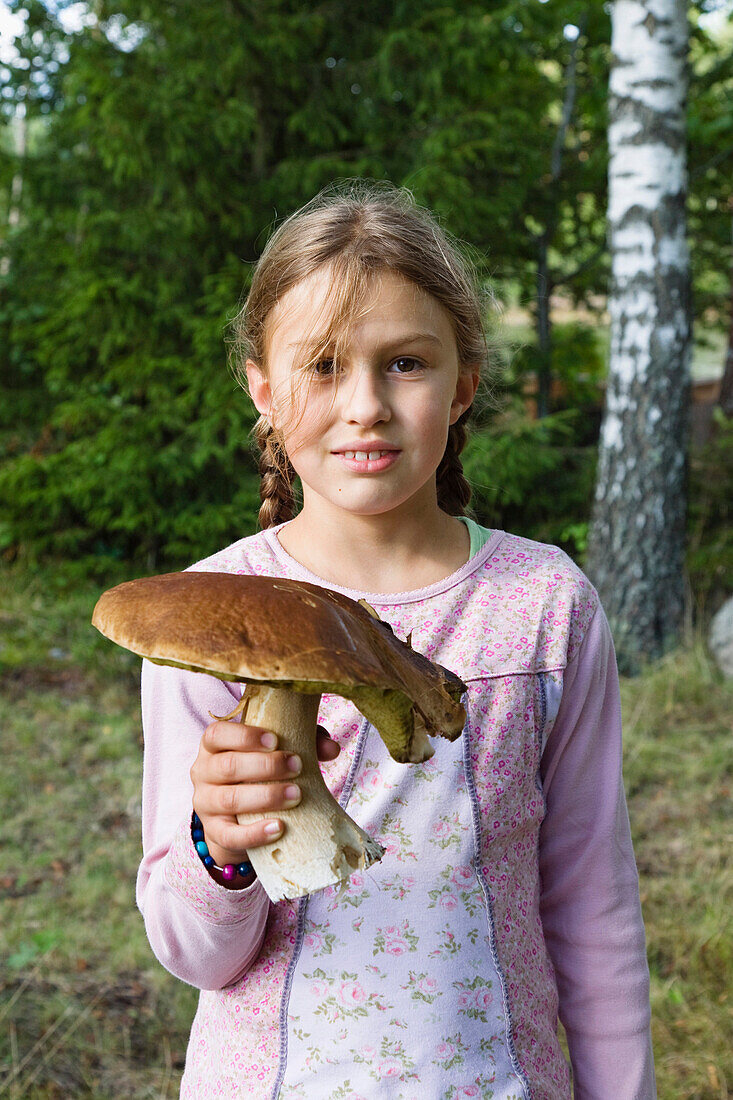 Mädchen (9 Jahre) hält einen Steinpilz, Smaland, Schweden